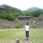 Aparna standing at a cultural site with mountains in the background