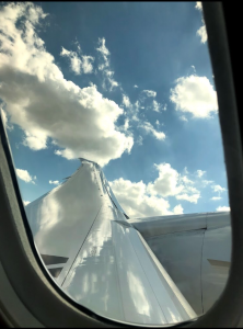 view from left side plane window with puffy clouds