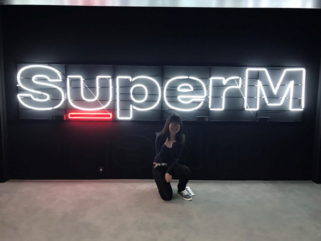 posing in front of SuperM neon sign