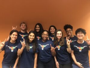 Coworkers together in Flag Bevo shirts throwing up Hook 'Em hand sign