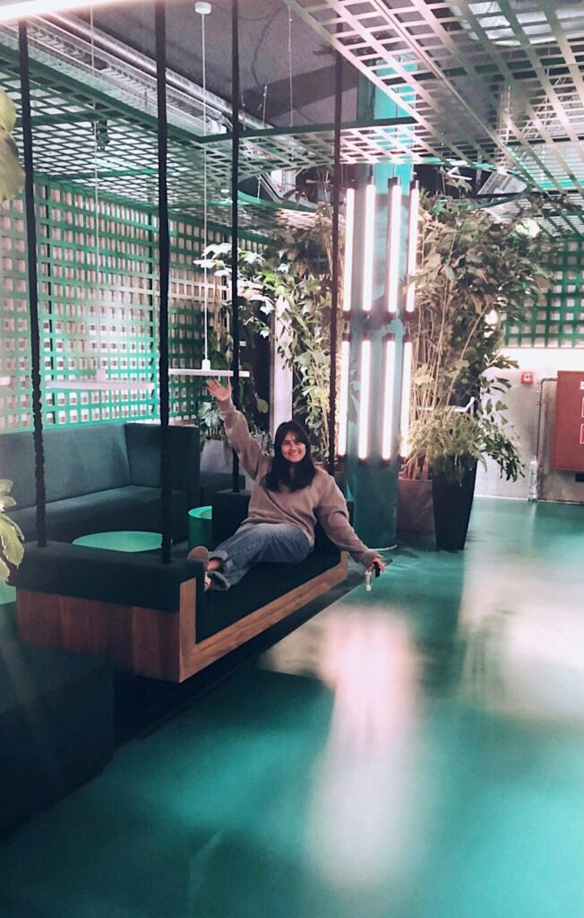 woman sits on couch in dimly lit lobby with decorative lighting and plants