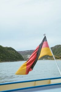 german flag on boat in body of water near hills during daytime