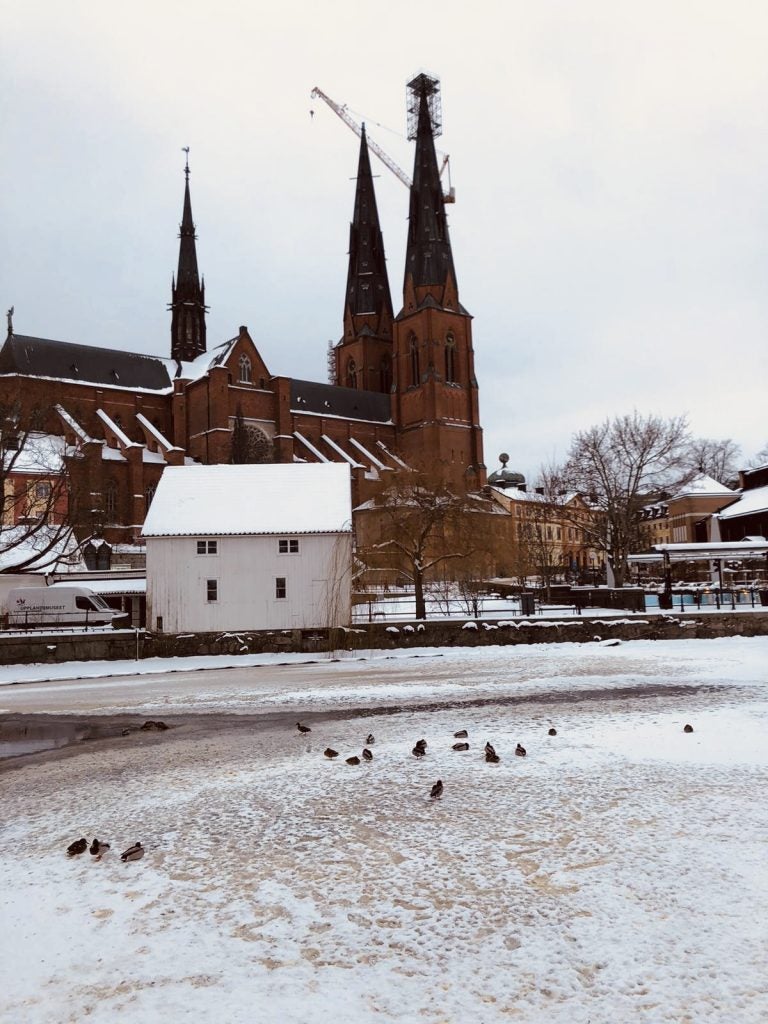 large historic building with spires near small white house in snowy city during daytime