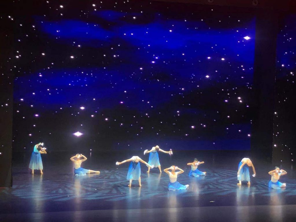 a group of people dance on a blue stage 