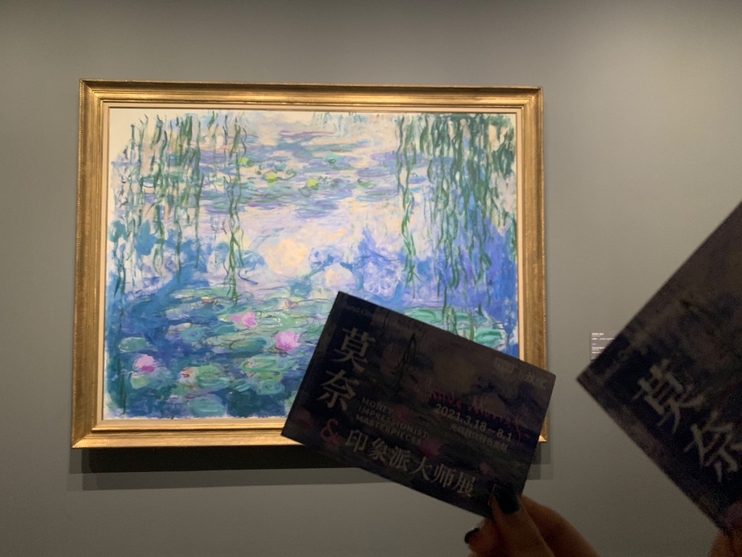 a monet painting on a wall with a person's hand in front of it