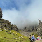 The Old Man of Storr, a unique rock formation on the Isle of Skye that is actually a massive, ancient landslide. Around the formation, a misty blue sky.