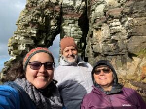 Downie smiles with her parents in front of the crags of Shetland. 