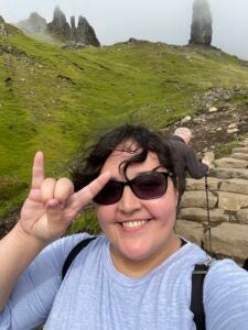  Downie smiles and shows the "hook 'em" hand sign while hiking to see the Old Man of Storr.