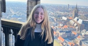 Katie smiles in front of a view of the Netherlands