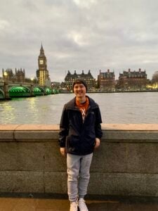 Devin smiles in front of a body of water. Behind him, Big Ben is visible