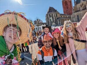 Katie and four friends smile while wearing fun accessories to celebrate Carnival