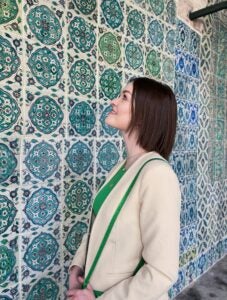 Eliza smiles in front of an intricate, blue-tiled wall in an Istanbul palace