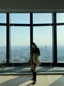 Mika stands in front of a window overlooking Tokyo at the Mori Art Museum