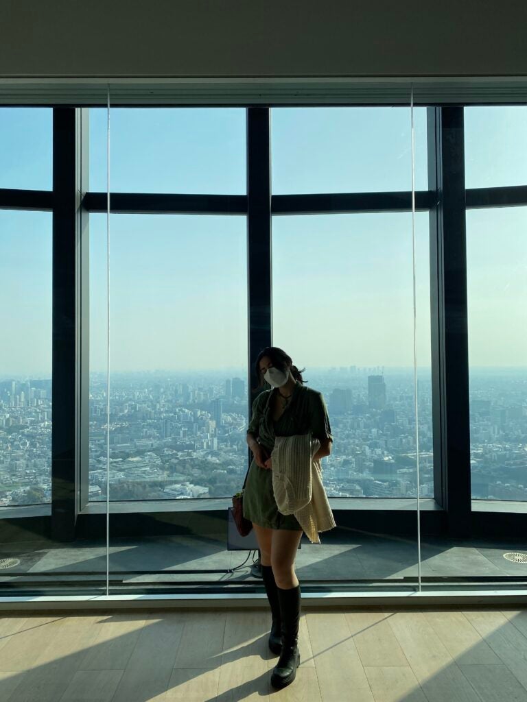Mika stands in front of a window overlooking Tokyo at the Mori Art Museum