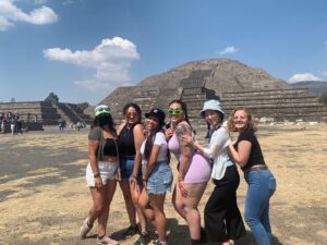 Jessica and five friends smile in front of the pyramid of the moon