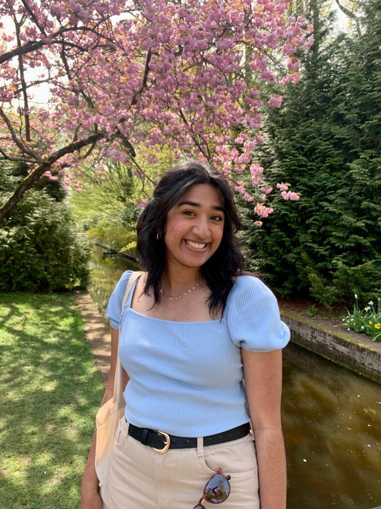 Anjali poses in front of a tree blooming with pink flowers