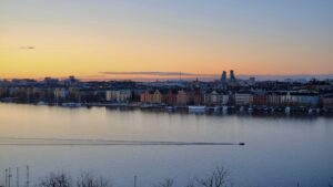 A sunset over a body of water with the city of Stockholm in the background