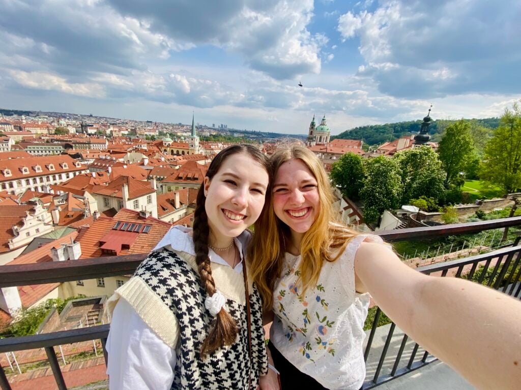 Katie Mulry and friend Sophie taking selfie in front of Prague, Czechia landscape.