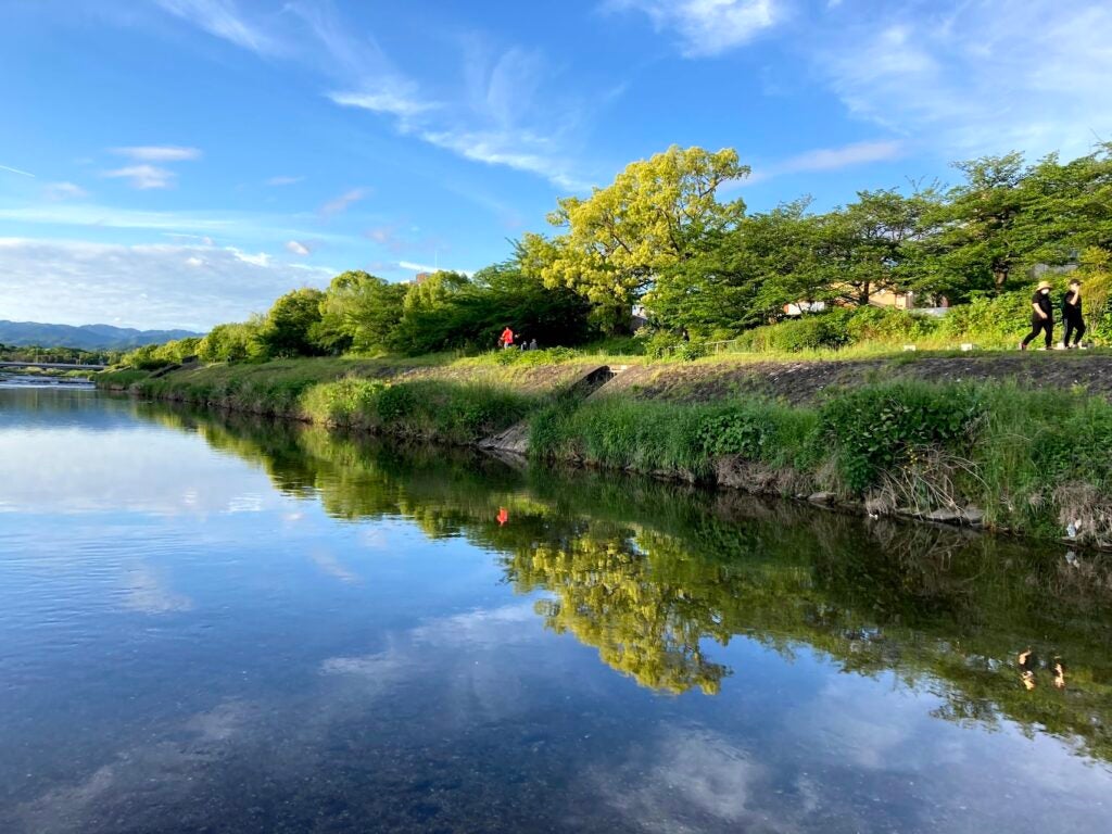 Two pedestrians and a bicyclists share the path next to the Kamogawa River in Kyoto