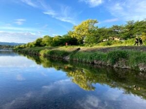 Two pedestrians and a bicyclists share the path next to the Kamogawa River in Kyoto 