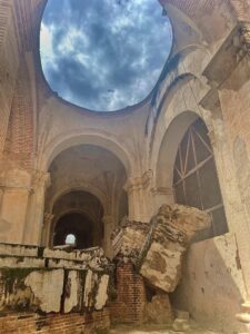 A cloudy blue sky shines from the oculus of an old cathedral in Antigua, Guatemala