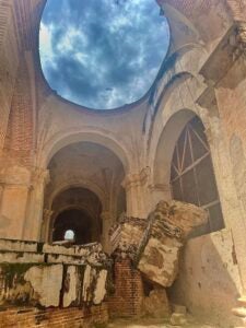 A cloudy blue sky shines from the oculus of an old cathedral in Antigua, Guatemala