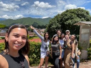 A group of students smile in front of the lush green mountains of Guatemala