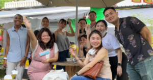 A group of interns smile and give peace signs outdoors at a cafe in Singapore