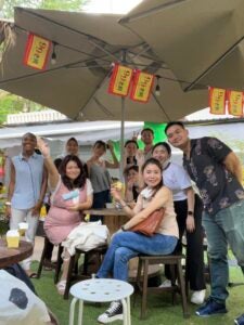 A group of interns smile and give peace signs outdoors at a cafe in Singapore