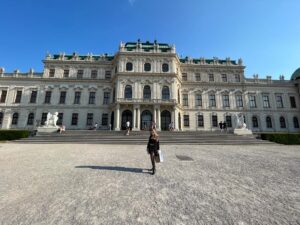 Gillian stands in front of a large white palace in Austria