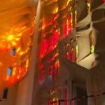 Red, orange and yellow light streams in through the painted glass windows at the Sagrada Familia