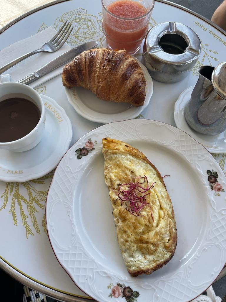 Omelette, croissant, coffee, and pink juice at a Parisian cafe