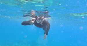 Man snorkeling doing hook 'em sign
