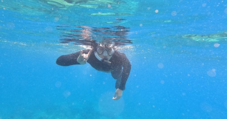 Man snorkeling doing hook 'em sign
