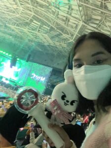Nina smiles with a plushie doll and a light stick in her hand