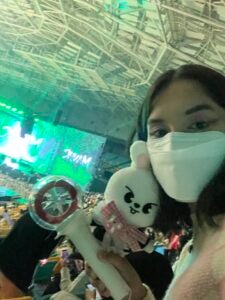 Nina smiles with a plushie doll and a light stick in her hand