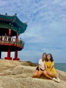 Nina and her friend, Lindsey sit together on a rock