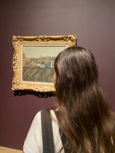The back of Amitai's head as she admires a painting in a museum