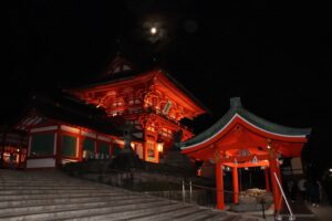 A red Japanese shrine against a moonlit background