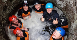 A group of students rappel down a canyon filled with water