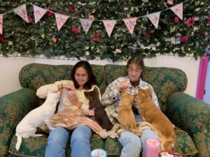 Gabby and friend Andrea sitting on a couch surrounded by Chihuahua dogs at a cafe