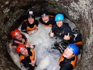 Peyton and friends sit in a hole of water during a guided canyoning trip