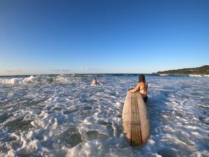 Peyton carries her surfboard out into the water