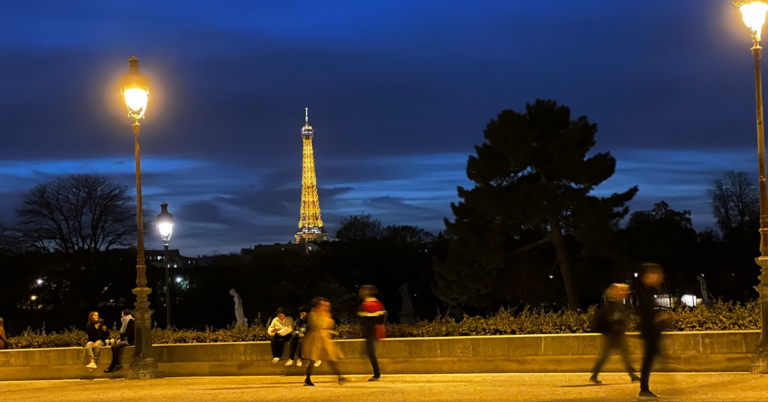 The Eiffel Tower is lit up golden at dusk