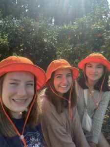 Nina and friends smile while wearing orange bucket hats