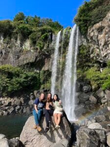 Nina and friends sit in front of a waterfall