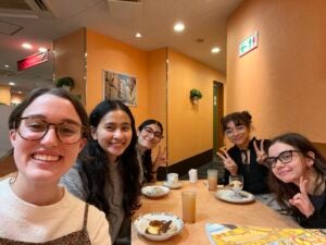 Claire and friends smile for a selfie inside a restaurant