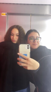 Vanessa and friend Zeynep take a mirror selfie in front of the elevators