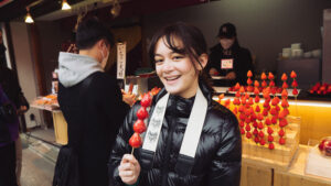 Cassidy smiles while holding skewered, candied strawberries