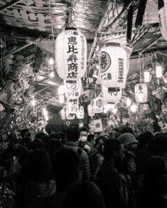 Lanterns hang over a street filled with festival goers